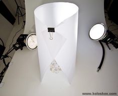 a white paper lamp with two clocks on the side and one light attached to it