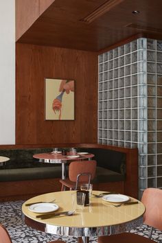 a table and chairs in a room with wood paneling on the wall behind it