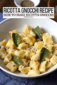 a white bowl filled with ravioli and sage on top of a blue cloth next to a