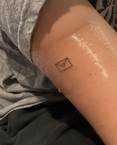 a person's arm with a small envelope tattoo on the left side of their arm