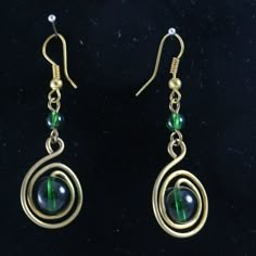 the earrings are made with wire and green glass bead, hanging from gold plated earwires