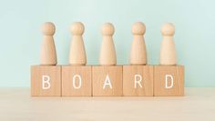 the word board spelled with wooden pegs in front of a blue wall and white background