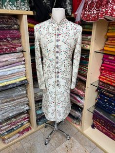 Men's Ivory sherwani with all-over blue and red thread embroidery ( French knot stitch with zardozi work). This sherwani is an easy to match with most lehengas Comes with Ivory churidars. Crafted with a collar neckline, full sleeves, and front button closure. Occasion: Can be worn to events like Wedding WASH CARE INSTRUCTIONS - Please Dry clean only when it is applicable. Slight color variation is possible due to digital photography. Fitted Embroidered Jamawar Sherwani, Embroidered Fitted Jamawar Sherwani, Fitted Jamawar Sherwani With Intricate Embroidery, Embroidered Long Jamawar Bandhgala, Long Embroidered Jamawar Bandhgala, Ceremonial Long Cream Sherwani, Wedding Sherwani With Floral Embroidery In Traditional Drape, Wedding Sherwani With Floral Embroidery And Traditional Drape, Fitted Off White Embroidered Traditional Wear