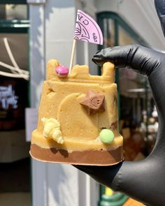 a hand holding up a cake shaped like a castle