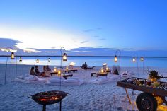 people are sitting on bean bags at the beach with lit candles in front of them