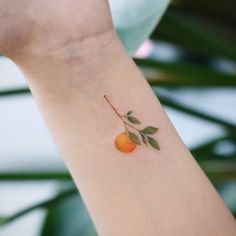 an orange tattoo on the arm of a woman's left arm, with leaves growing from it