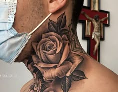 a man with a rose tattoo on his neck is wearing a medical mask and looking at the camera