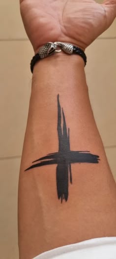 a person with a cross tattoo on their arm