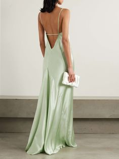 the back of a woman wearing a green dress and holding a white clutch in her hand