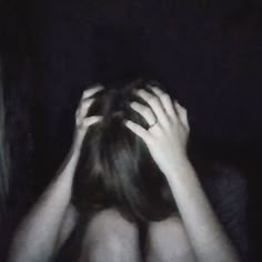 two people covering their faces in the dark with their hands on their head and one person's back to the camera