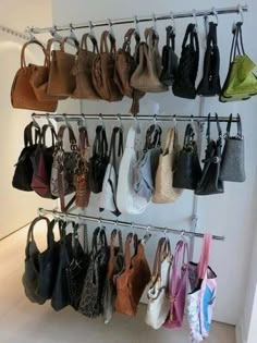 several purses are hanging on a rack in front of a white wall and floor