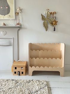 a wooden toy house sitting next to a fire place in a room with a rug on the floor