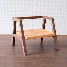 a wooden chair sitting on top of a hard wood floor next to a white tiled wall