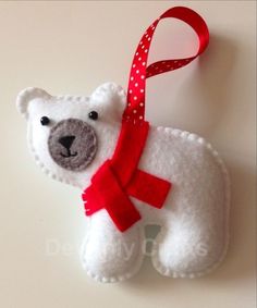 a white bear ornament with a red ribbon hanging from it's neck