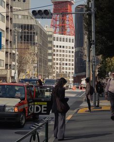 people are walking down the street in front of some tall buildings and traffic lights on a sunny day