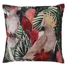 two birds sitting on top of a pillow with tropical leaves and flowers around the edges