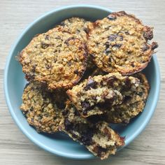 a blue bowl filled with oatmeal and raisin muffins on top of a wooden table