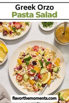 greek pasta salad on a plate with lemons, tomatoes and cucumbers