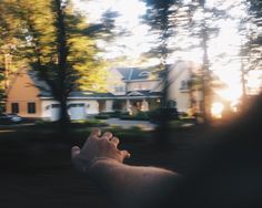 a person holding their hand out to the sun in front of a large white house