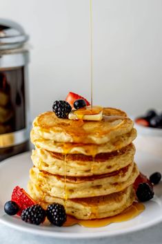 a stack of pancakes with syrup and berries