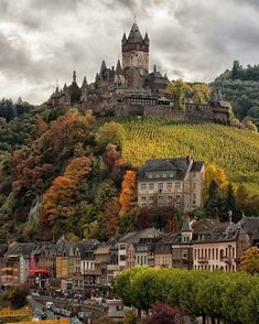 an old castle on top of a hill surrounded by trees and other small town buildings