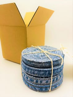 a cardboard box and stack of blue jeans sitting next to each other on a white surface