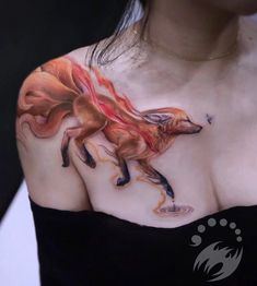 a woman's chest with a tattoo of a fox and fire on it,