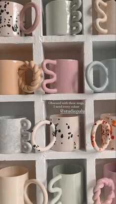 many different colored coffee mugs are arranged in a grid on a white wall with letters and numbers