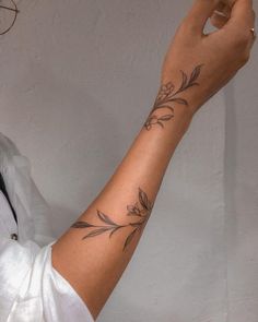 a woman with a flower tattoo on her arm holding a cell phone up to the camera