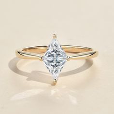 a yellow gold ring with a pear shaped diamond in the center, on a white background