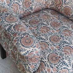 an upholstered chair with floral fabric on it's seat and back cushions