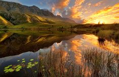 the sun is setting over a mountain lake