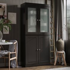 a black cabinet with glass doors in a room next to a table and chair on the floor