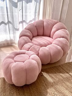 a pink chair and ottoman sitting on top of a carpeted floor next to a window