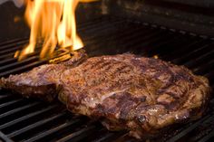 a steak is cooking on the grill with flames