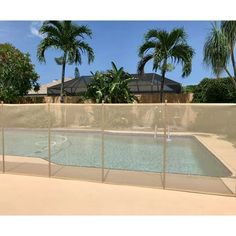 a fenced in swimming pool surrounded by palm trees