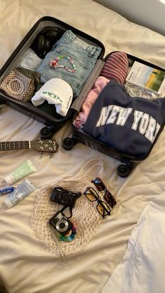 an open suitcase sitting on top of a bed with clothes and other items in it