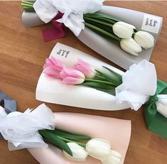 three bouquets of tulips are wrapped in white paper and tied with ribbon