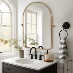 a bathroom sink sitting under a large mirror next to a white counter top with a potted plant on it