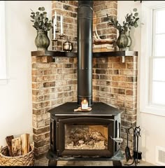 a wood burning stove in front of a brick wall with potted plants on top