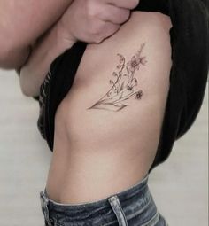 a woman's lower back tattoo with flowers on her left side ribcage