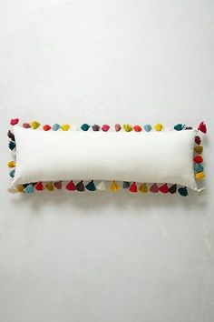 a white pillow with multicolored pom - poms on the front and back