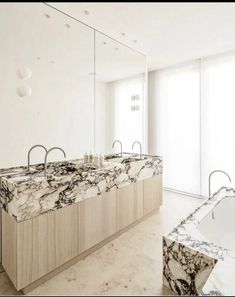 a large bathroom with marble counter tops and mirrors on the wall, along with two sinks