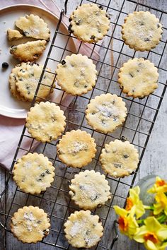 cookies cooling on a wire rack next to flowers and a white plate with blueberries