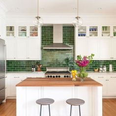 a kitchen with two stools next to an island