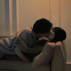 a man and woman are kissing on a couch