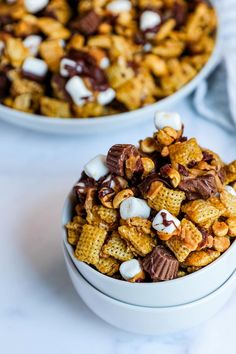 two white bowls filled with chocolate and marshmallows on top of a table