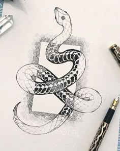 a drawing of a snake on paper next to some pens and inking utensils