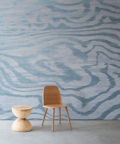 a chair and stool in front of a wall painted with blue swirls on it