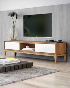 a living room with a large television on top of a wooden entertainment center in front of a white wall